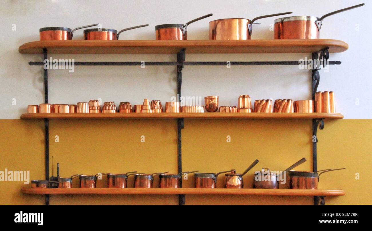 Bellissimo il rame pentole e padelle disposti su scaffalature contro un due tonalità di sfondo di giallo e bianco - Immagine stock catturata con smartphone