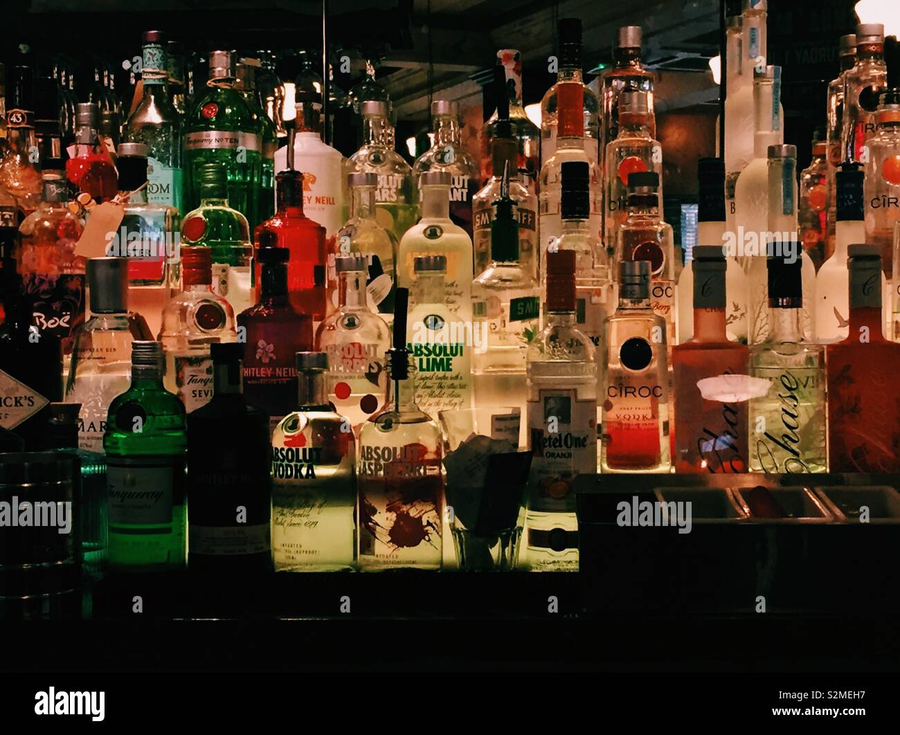 Bottiglie colorate alcolici in bar Foto Stock