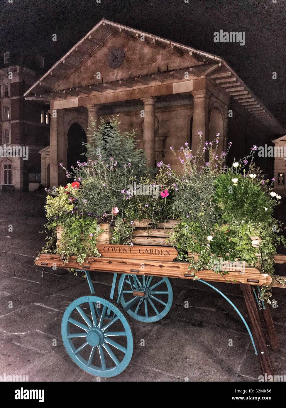 Carriola in legno pieno di fiori in Covent Garden di Londra di notte Foto Stock