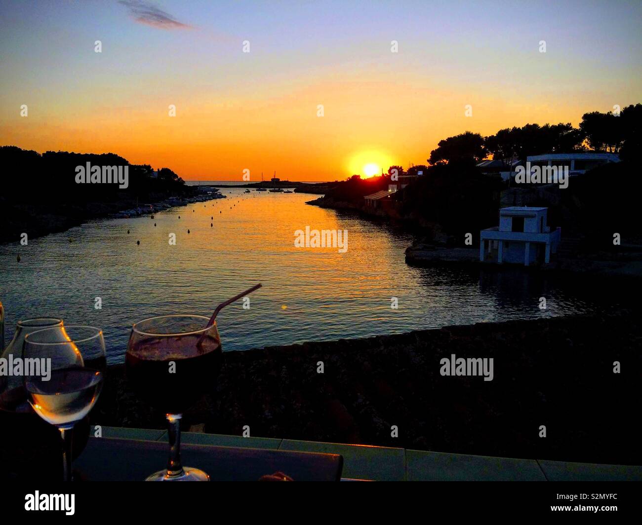 Alcune bevande mentre il tramonto, baia di Santandria, Menorca, Spagna Foto Stock