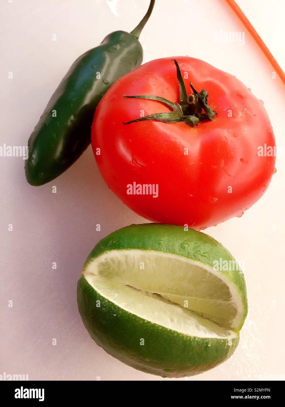 Ancora vita close up di un verde jalapeño pepe, vine stagionati di pomodoro e fettine di lime Foto Stock