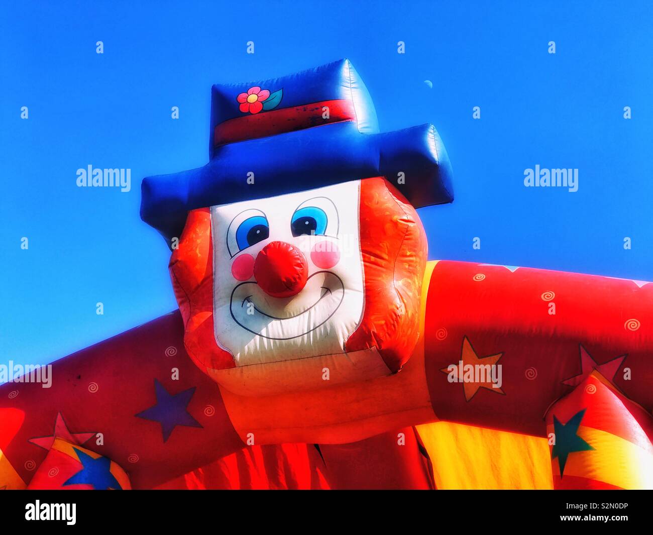 Il volto di un clown adorna di un castello gonfiabile a un inglese divertente fiera (fun fayre). È estate, il cielo è blu - è il momento di divertirsi! Credito foto © COLIN HOSKINS. Foto Stock