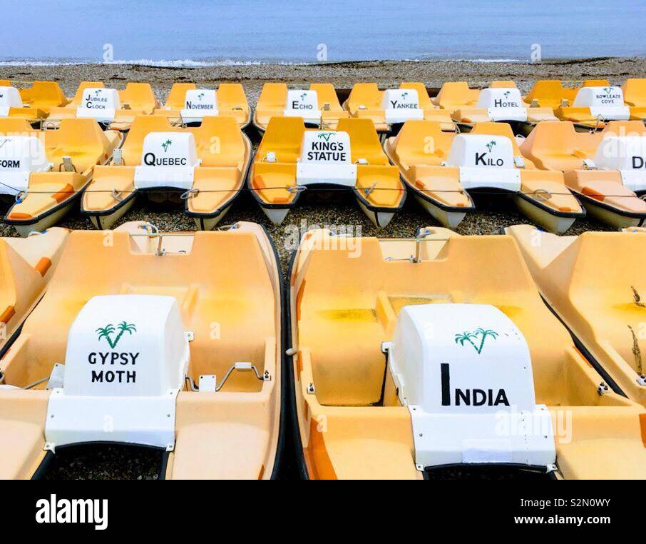 Righe di colore arancio brillante denominato pedalò a Weymouth beach Foto Stock