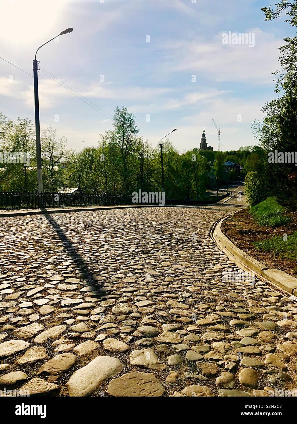 L'ombra del pilastro sulla strada fiancheggiata con pietre Foto Stock