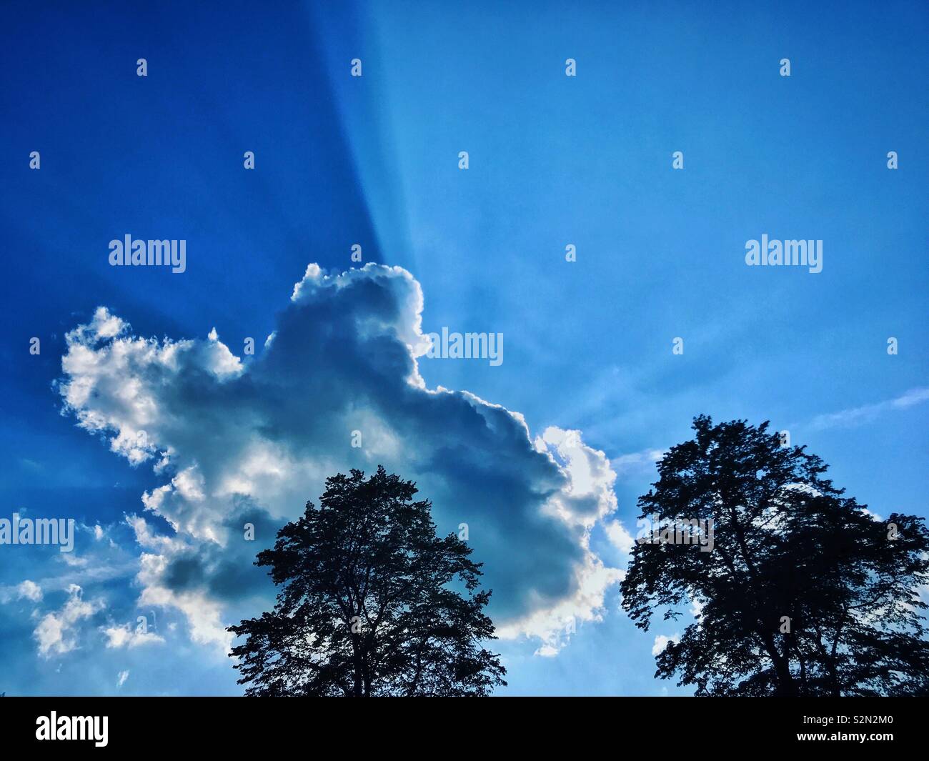 Raggi crepuscolari di luce solare sparare fuori da dietro un argento rivestita cloud. Questi raggi di luce vengono anche chiamati raggi scheggiati, Dio con le dita, raggi solari, gli alberi dal cielo e raggi di sole. Foto © COLIN HOSKINS - Immagine stock catturata con smartphone