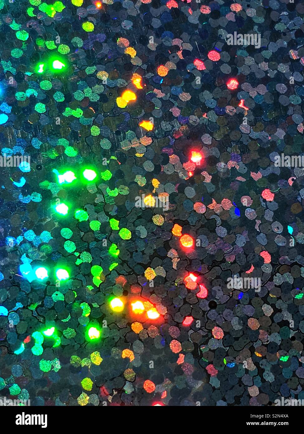 Blu brillante, giallo, arancio e verde colorato olografica, abstract e disposizione prismatico di piccoli minuscoli paillettes Riflettere alla luce. Foto Stock