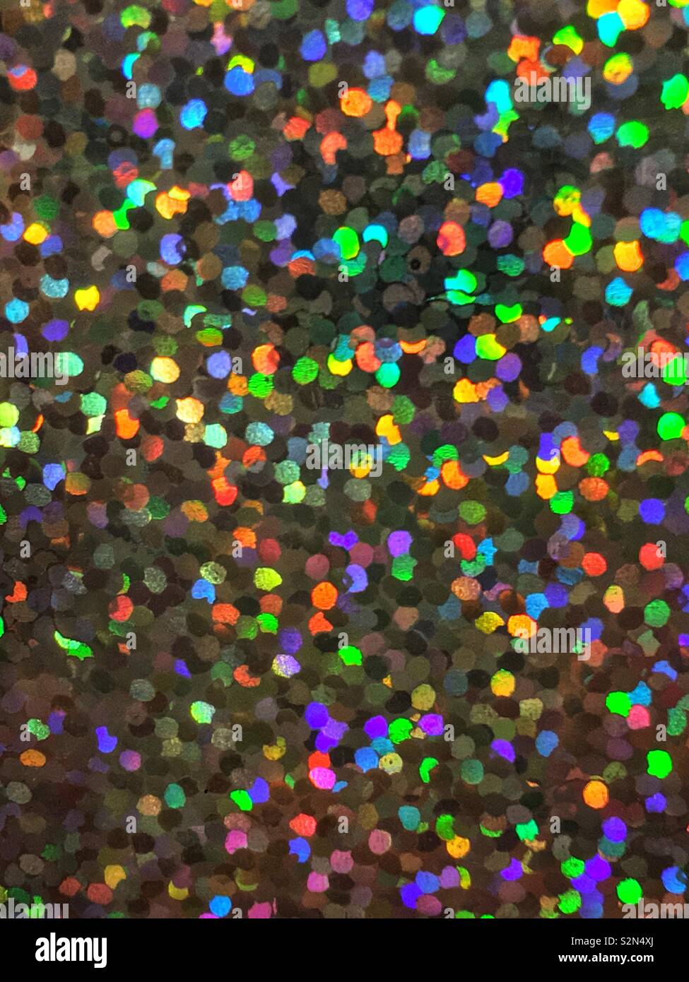 Blu brillante, giallo, arancio e verde colorato olografica, abstract e disposizione prismatico di piccoli minuscoli paillettes Riflettere alla luce. Foto Stock