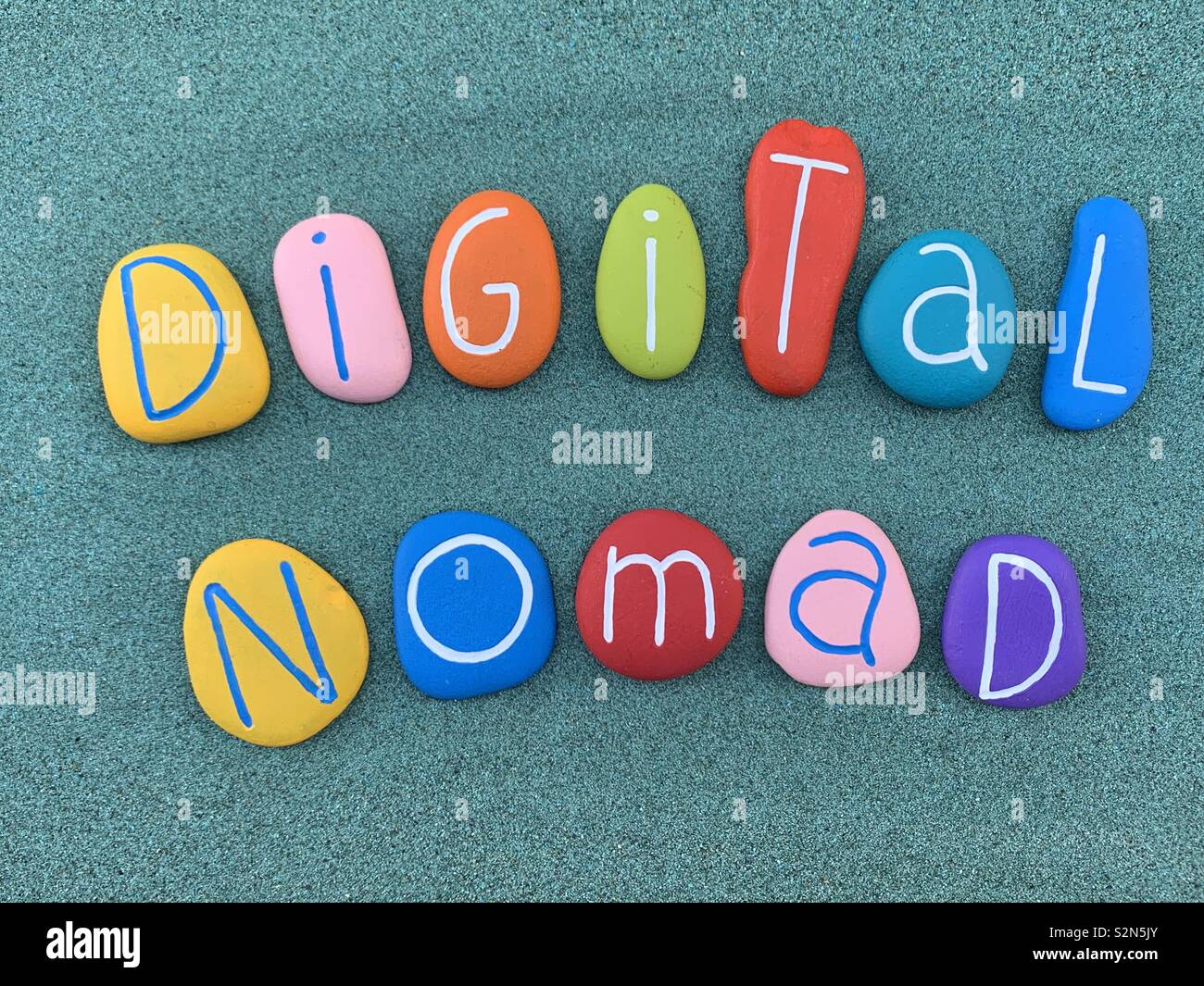 Il nomade digitale, nuovo profilo di lavoro composto di testo con multi colore pietre di mare sulla sabbia verde Foto Stock