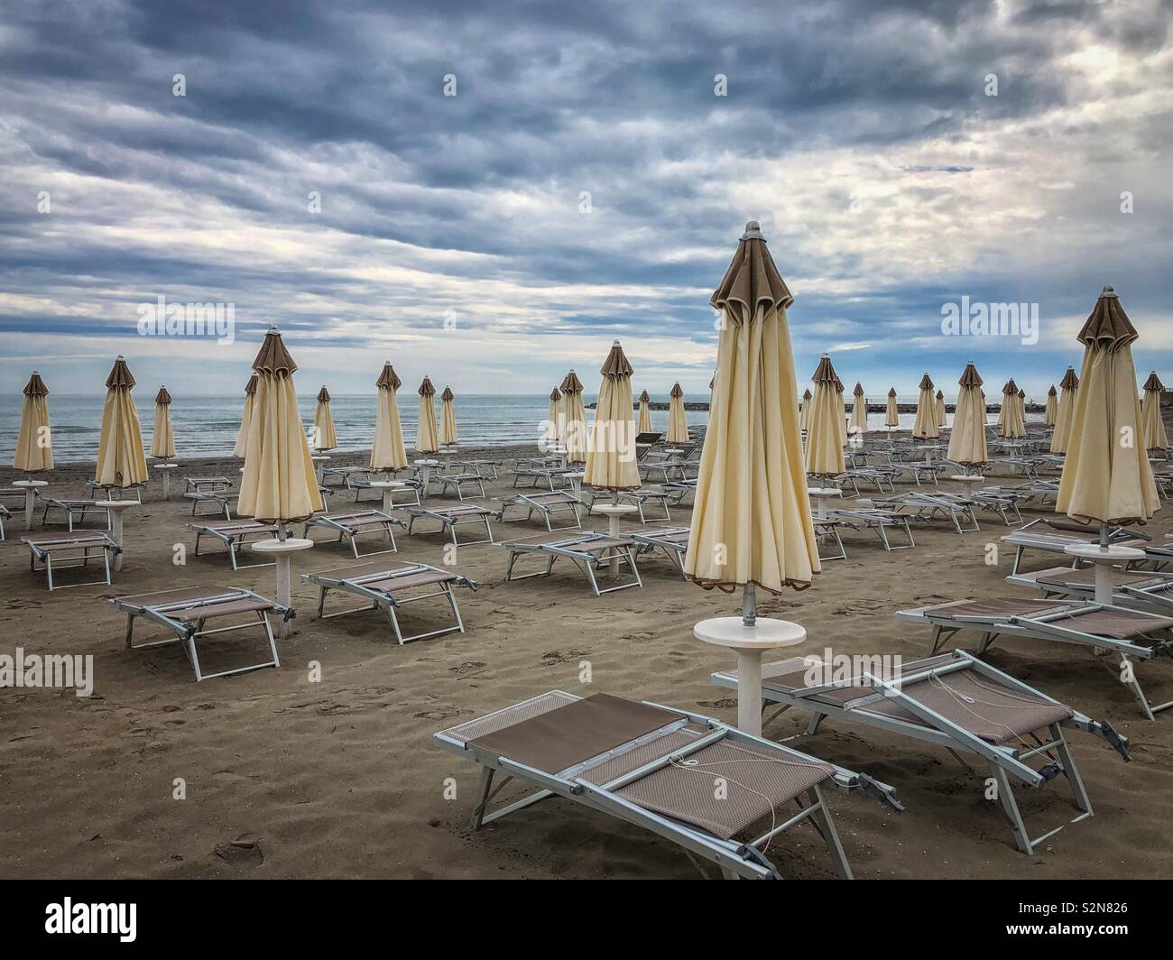 Vuoto spiaggia con sedie a sdraio e ombrelloni piegato - Grado Friuli  Venezia Giulia, Italia Foto stock - Alamy