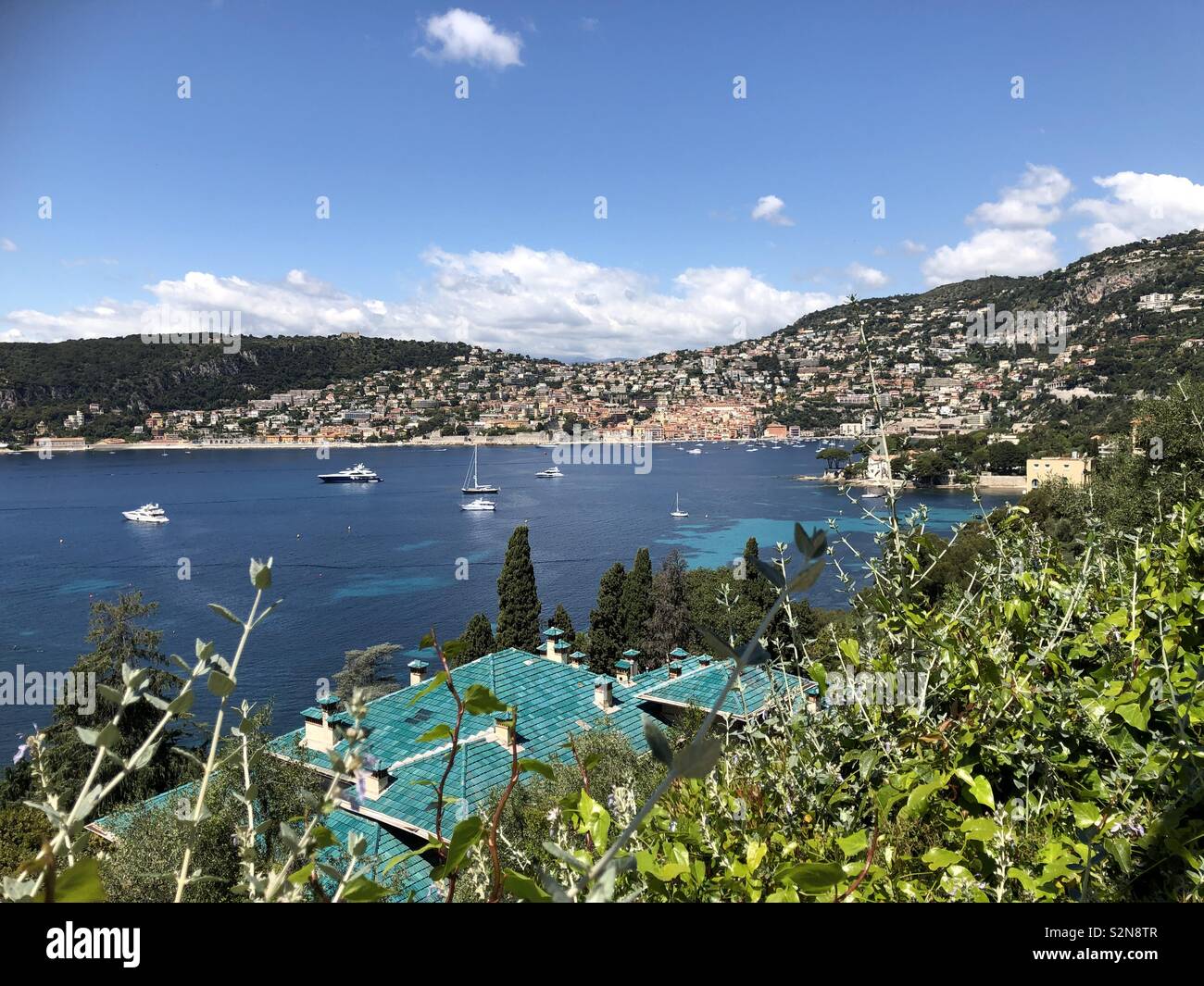 Villefranche-sur-Mer vista dal giardino di Villa Ephrussi attraverso la baia e Boat Harbour e comprendente una villa con verde piastrelle smaltate. Foto Stock