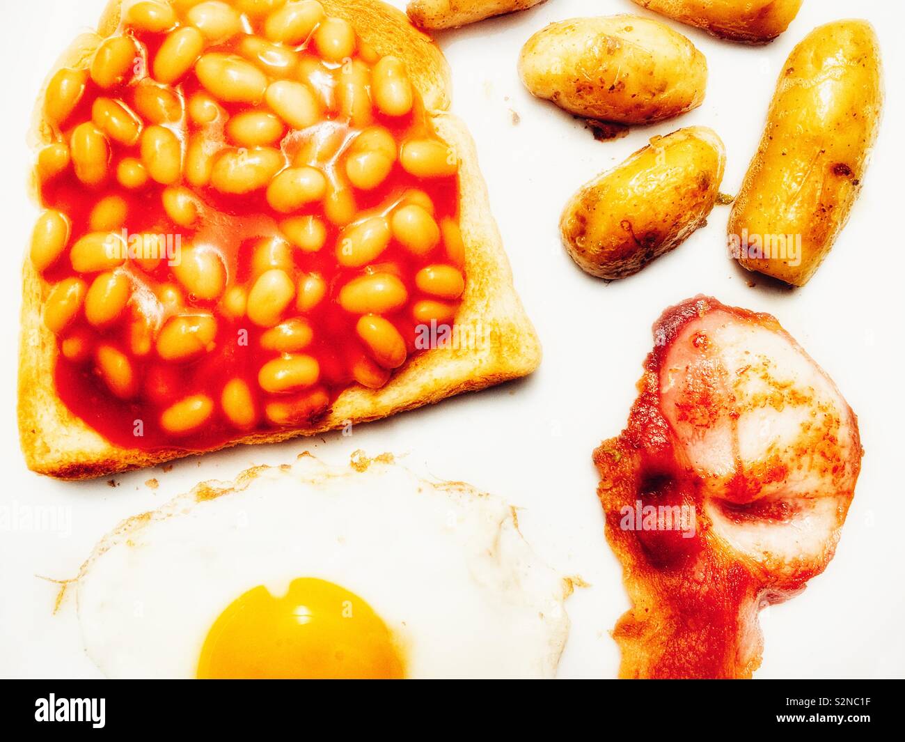 Fagioli al forno su toast fritti con patate di primizia, uova e pancetta. Foto Stock