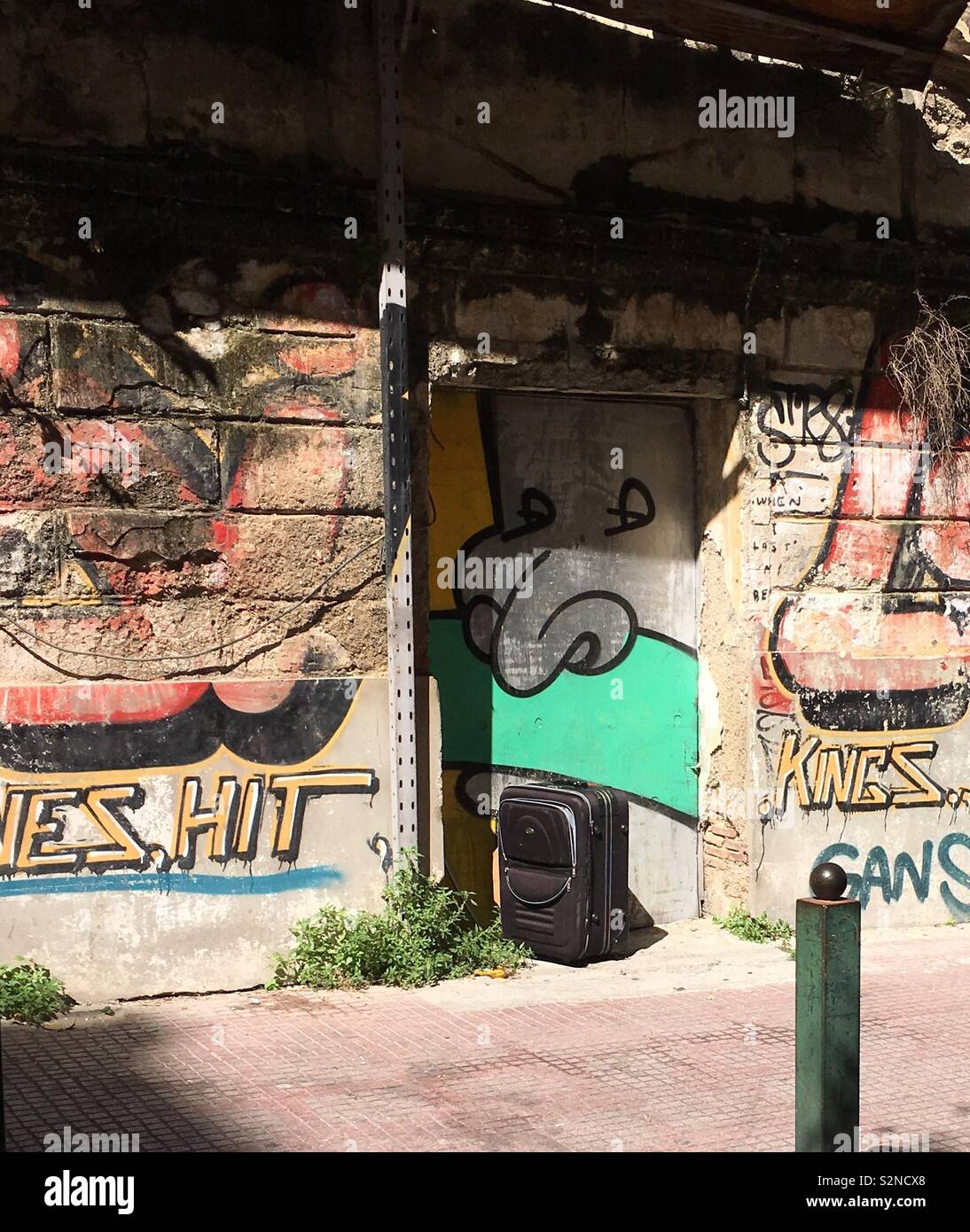 Abbandonata la valigia nella porta di graffiti-disseminata derelitti, abbandonato edificio storico nel centro di Atene, Grecia. Foto Stock