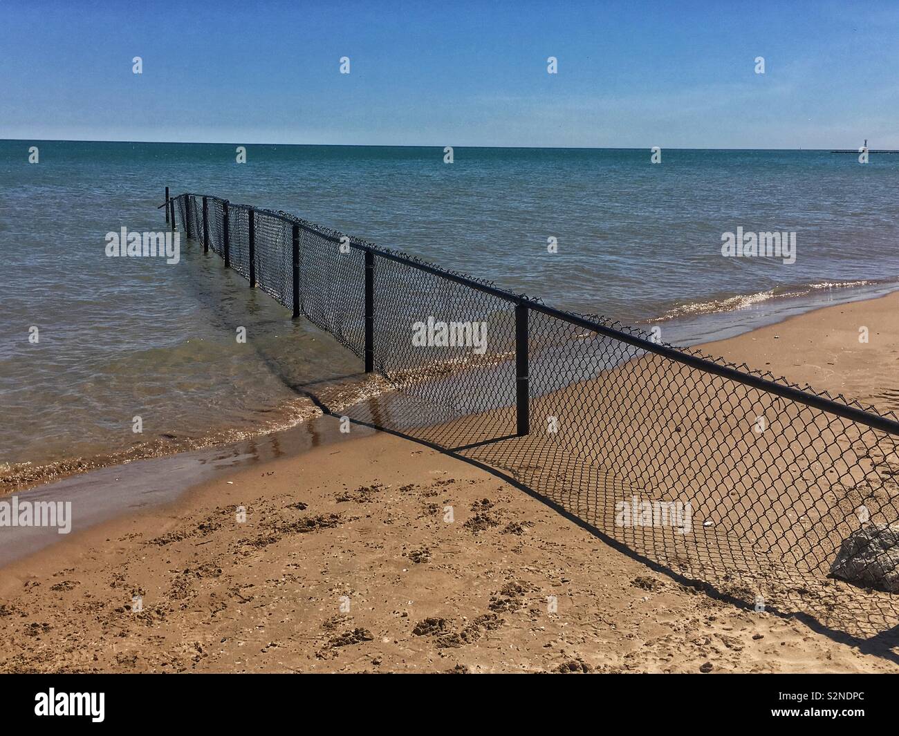 Nero catena collegamento recinto andando nel lago Michigan e la separazione di due spiagge. Foto Stock