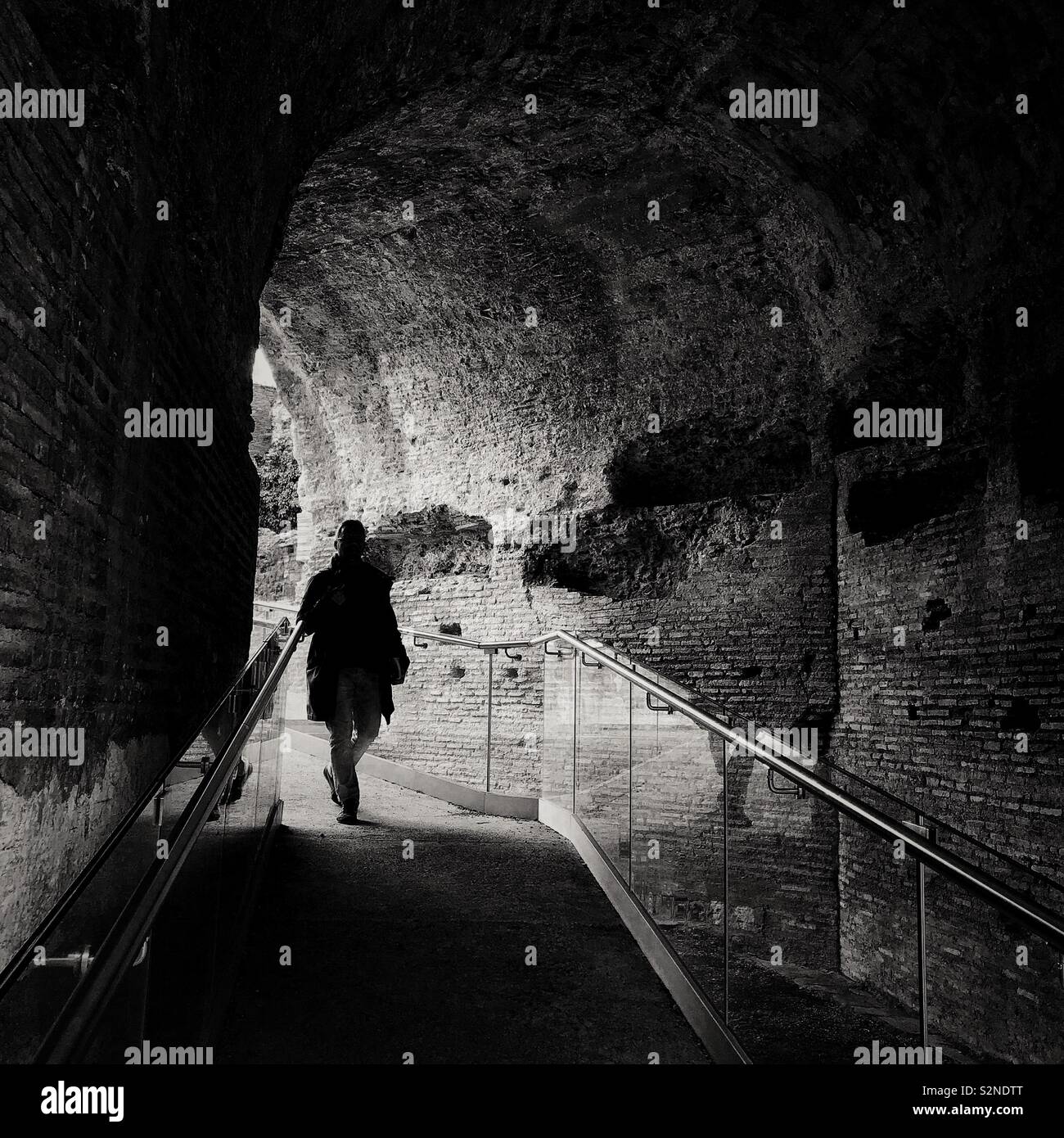 Silhouette di una persona che cammina verso il basso una rampa attraverso un antico arco romano, Colle Palatino Roma Italia Foto Stock