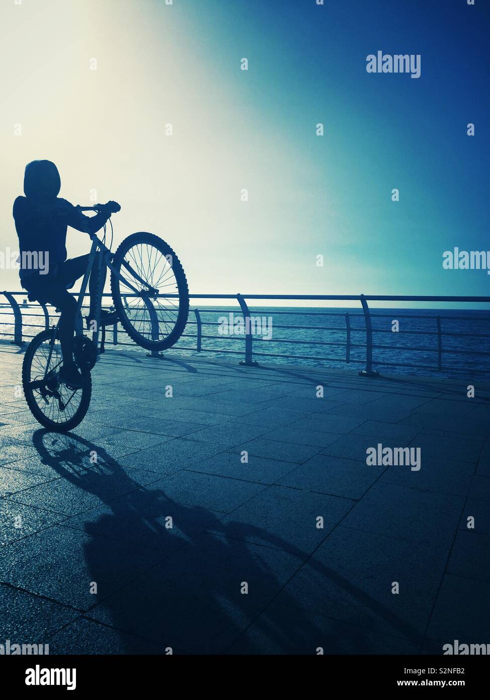 Ragazzo adolescente giocando sulla bici sulla spiaggia Foto Stock
