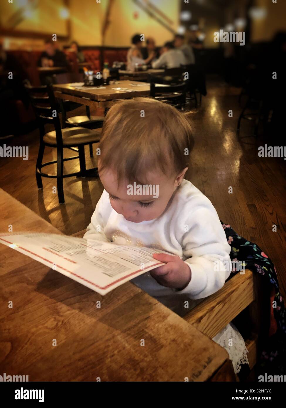 Baby la lettura del menu in un ristorante Foto Stock