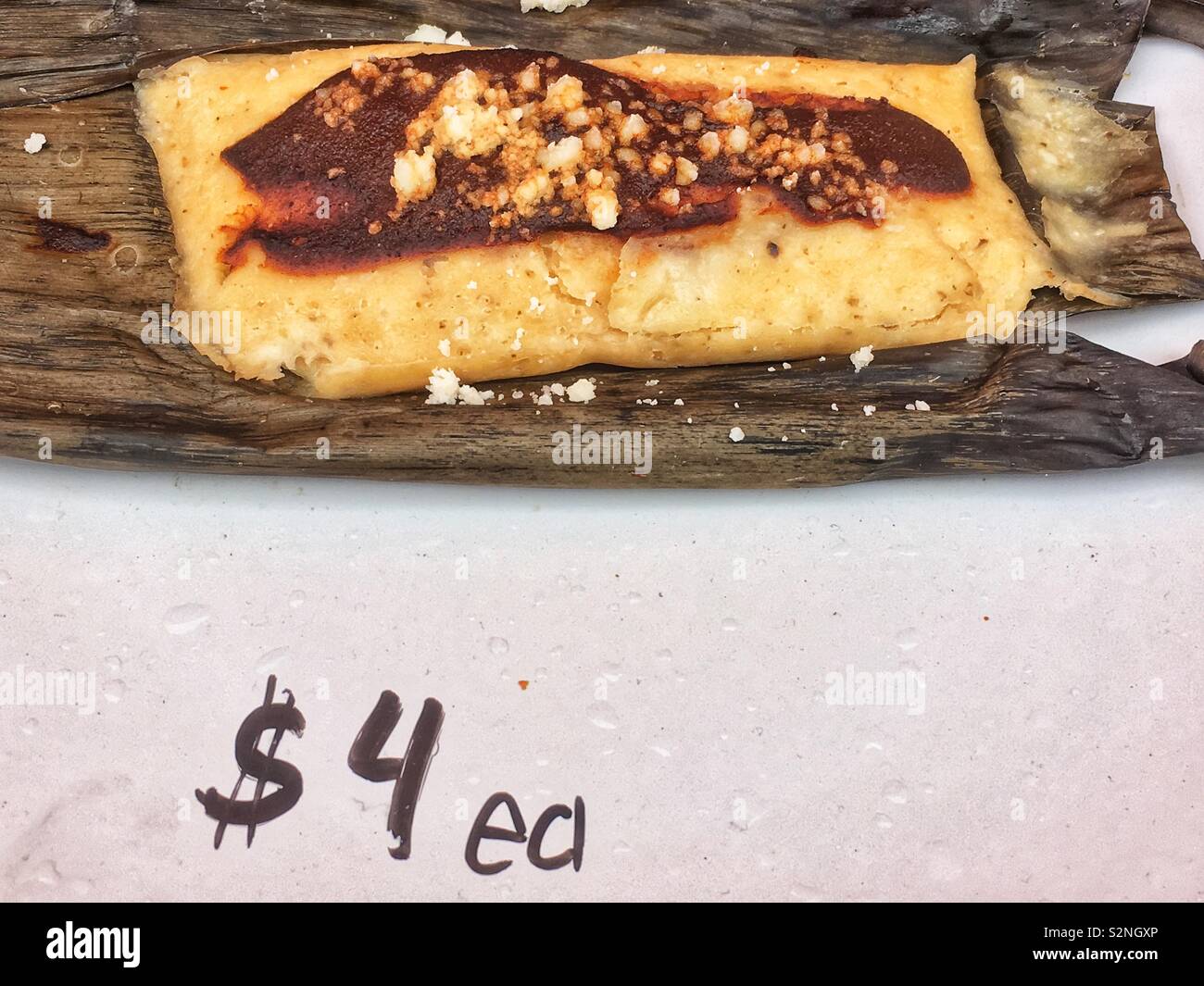 Piastra di display di un fresco tomale cotta su una buccia di mais per 4 dollari come messicano deliziosa cucina di strada. - Immagine stock catturata con smartphone