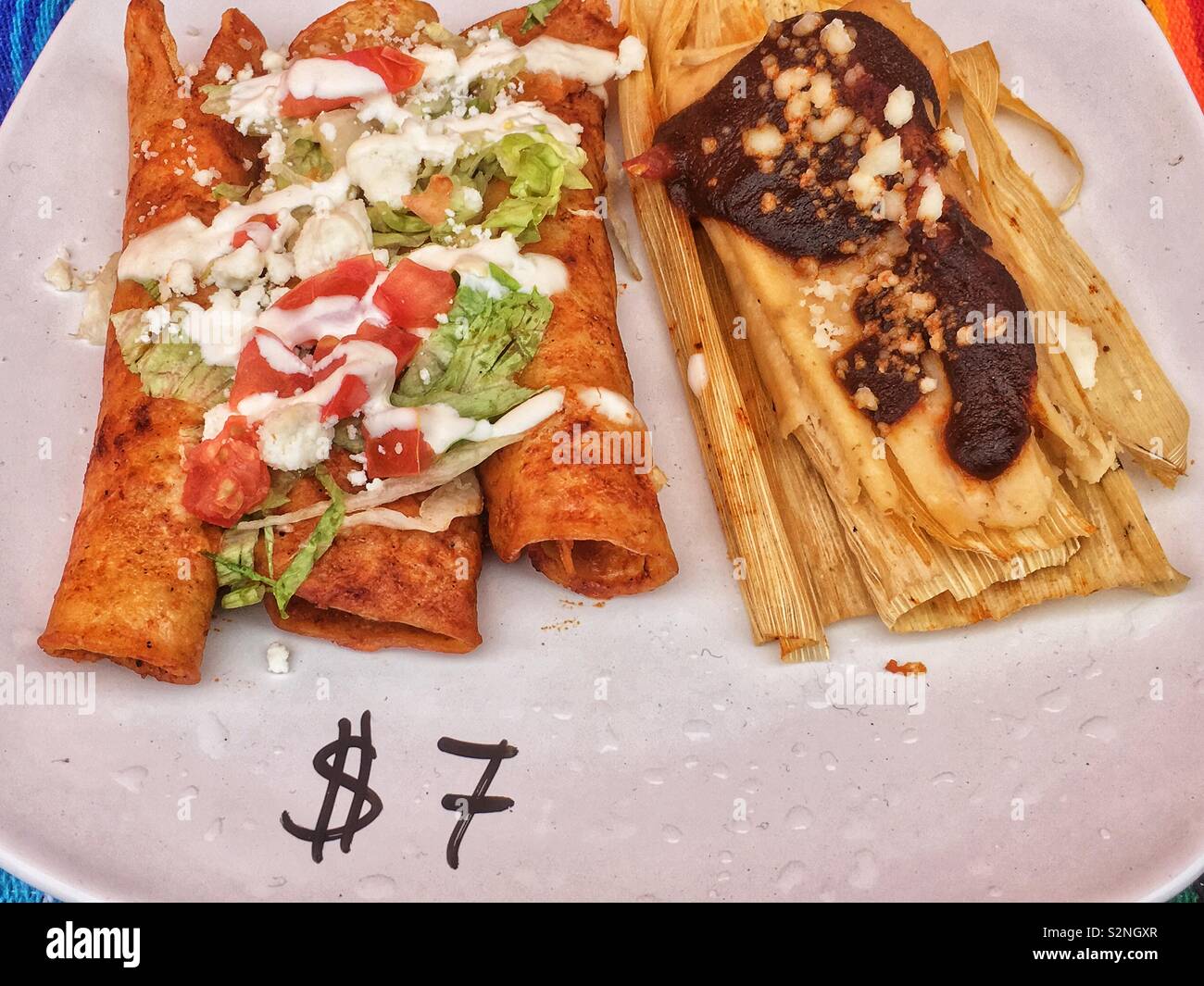 Display piastra combinata di un fresco tomale cotta su una buccia di mais e tre caricato chimichangas fritto per $7 come messicano deliziosa cucina di strada. - Immagine stock catturata con smartphone