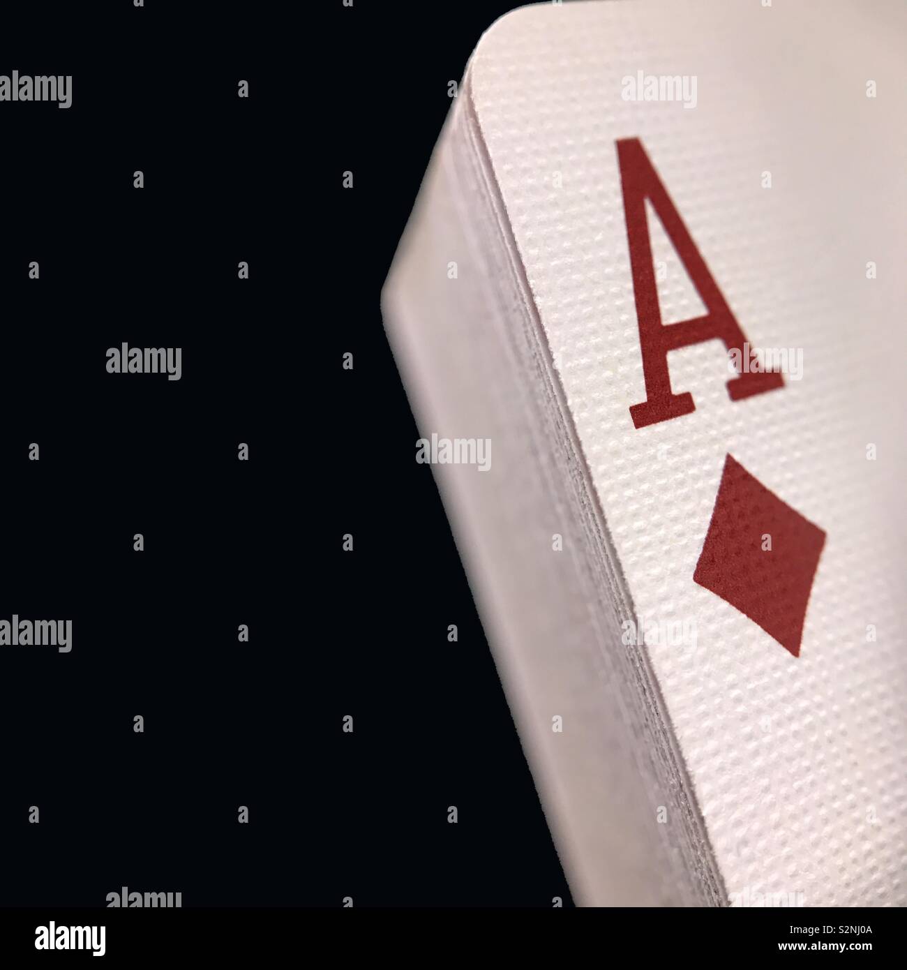 Un ordinatamente impilati mazzo di carte da gioco, con un asso di diamanti sulla sommità, è mostrato contro un solido sfondo nero con una stanza per copiare testo per lo spazio sulla sinistra. - Immagine stock catturata con smartphone