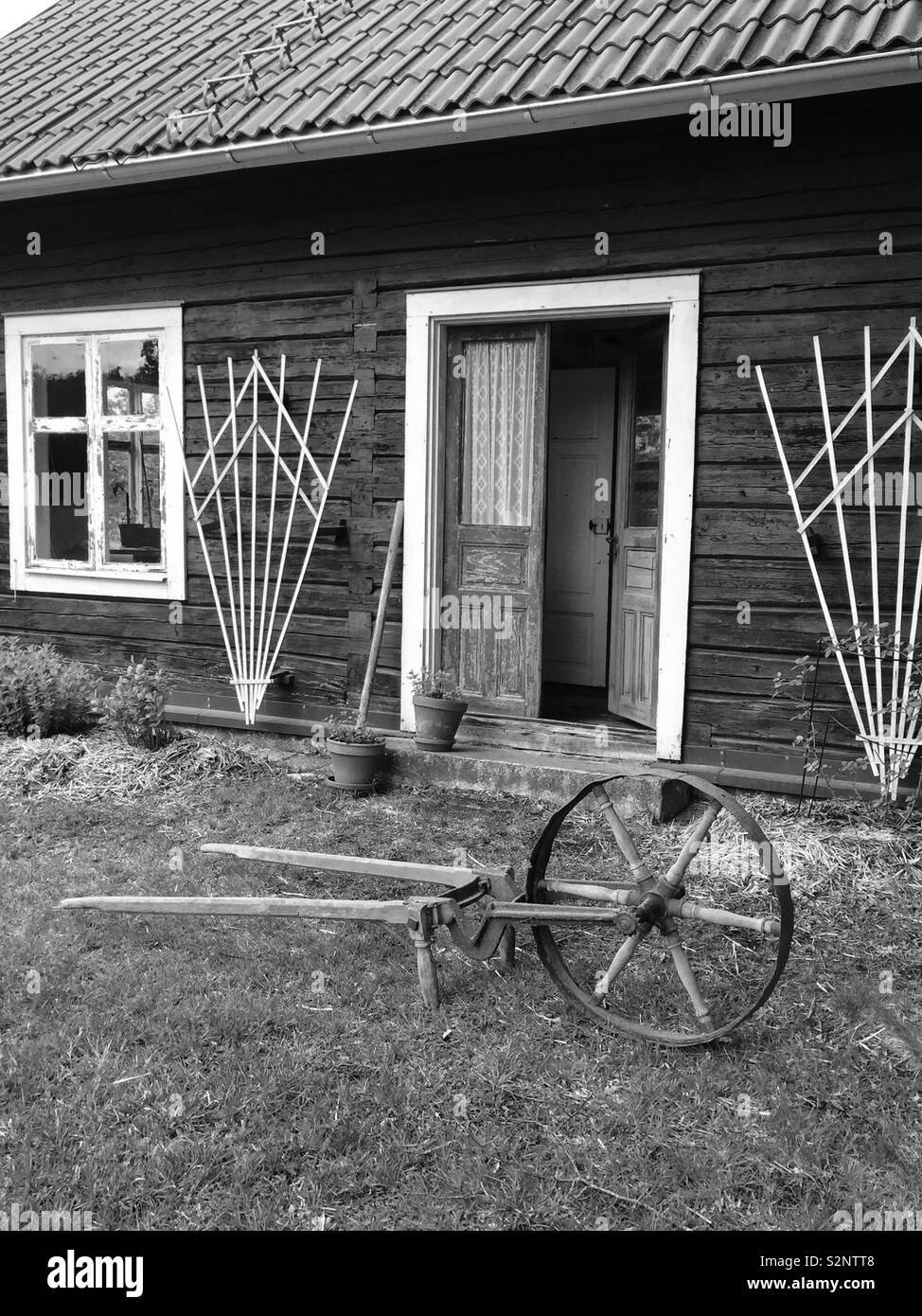 Il vecchio strumento agricolo di fronte un log house, vecchio insediamento in Svezia. Foto Stock