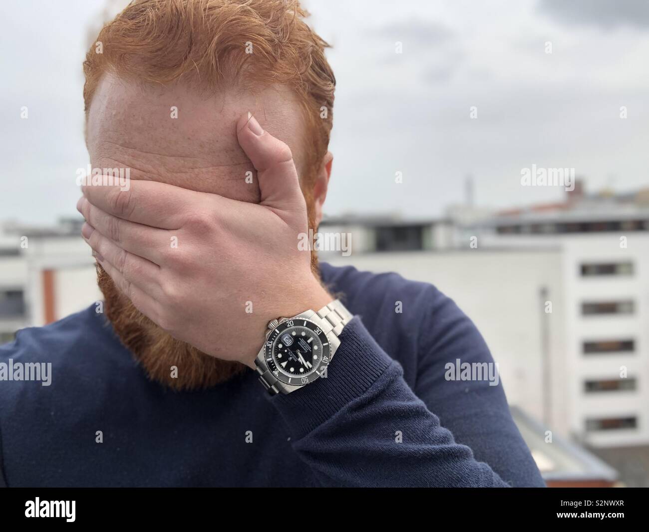 Testa rossa copre gli occhi con orologio al polso Foto stock - Alamy