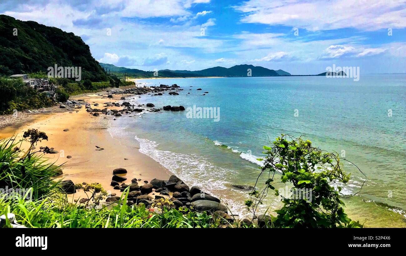 Una spiaggia condito con rocce si protende verso la penisola di montagne. Foto Stock