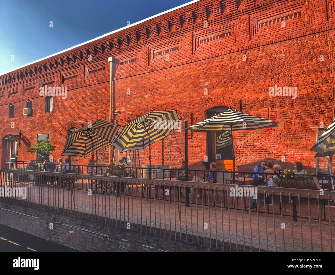 La gente fuori a cena nel patio lungo il lato di un vecchio edificio in mattoni del muro. Foto Stock