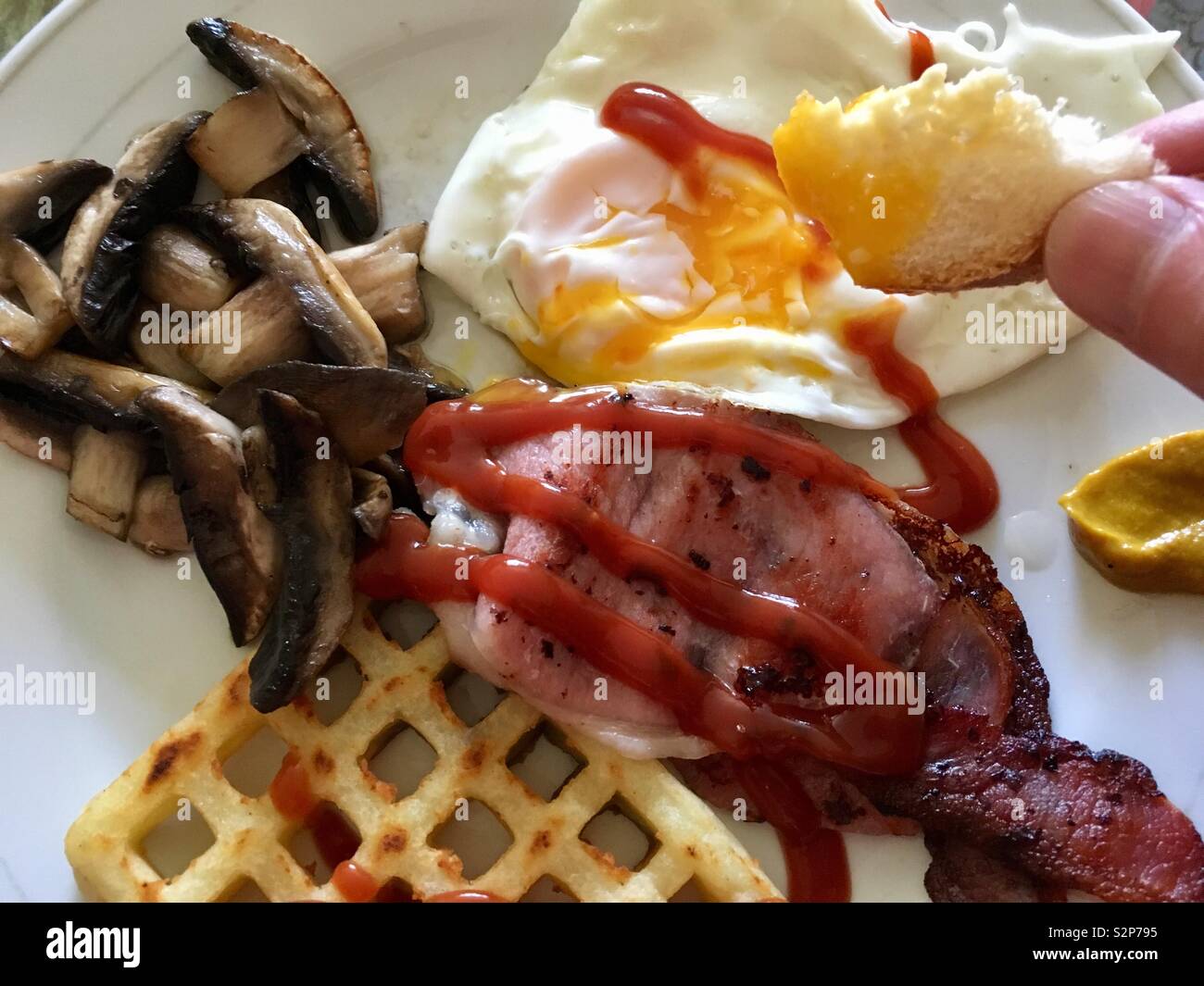 Intingere il pane in un uovo su una prima colazione inglese Foto Stock