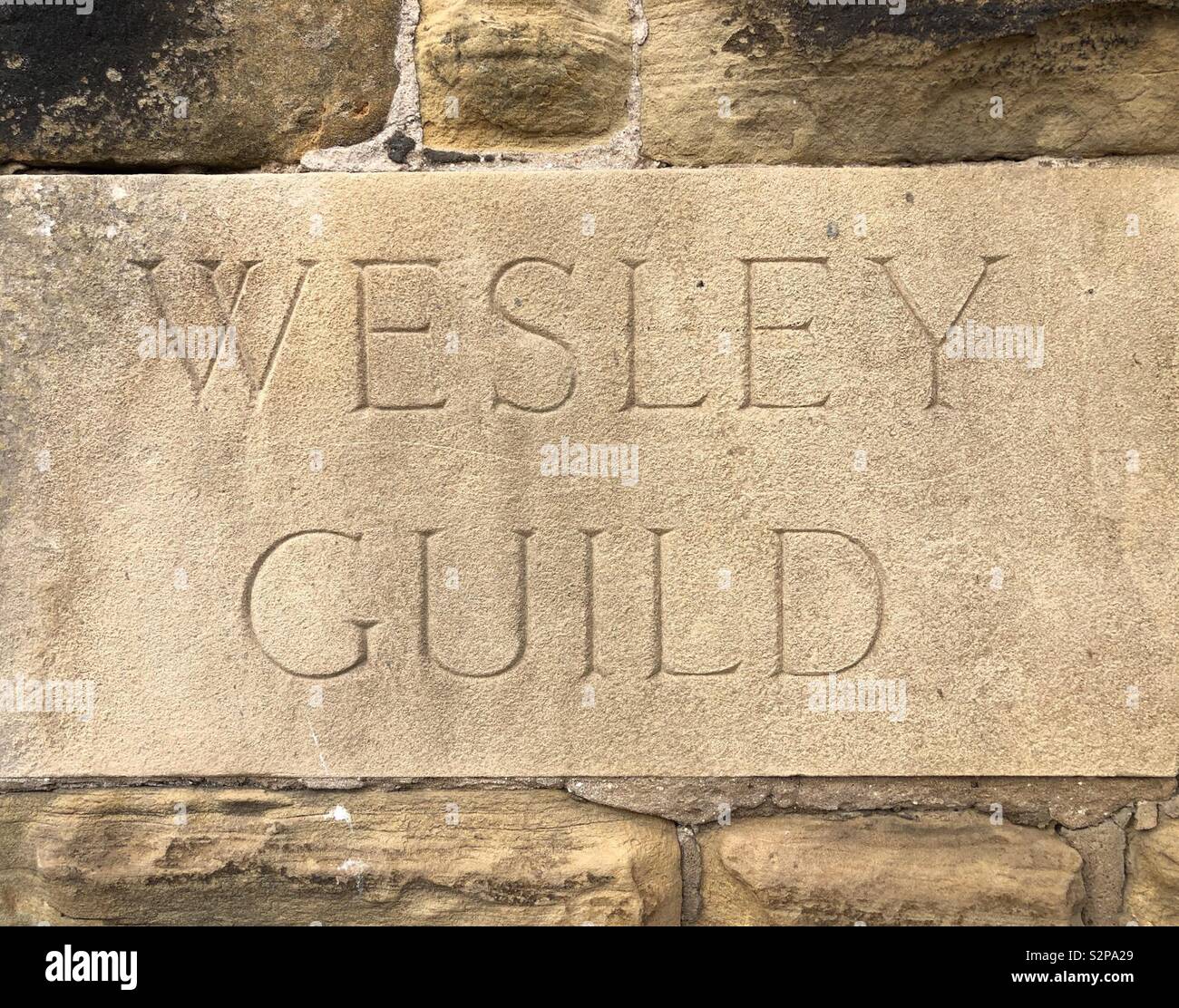 Pietra scolpita annegata nella parete di una chiesa metodista - Wesley Guild Foto Stock