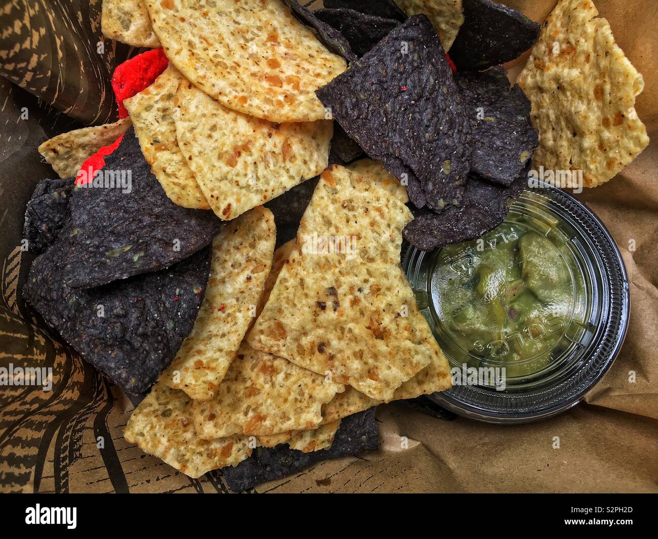 Varietà di rosso, blu e bianco corn chips impostato a fianco di una piccola vasca di fresco verde guacamole. Foto Stock