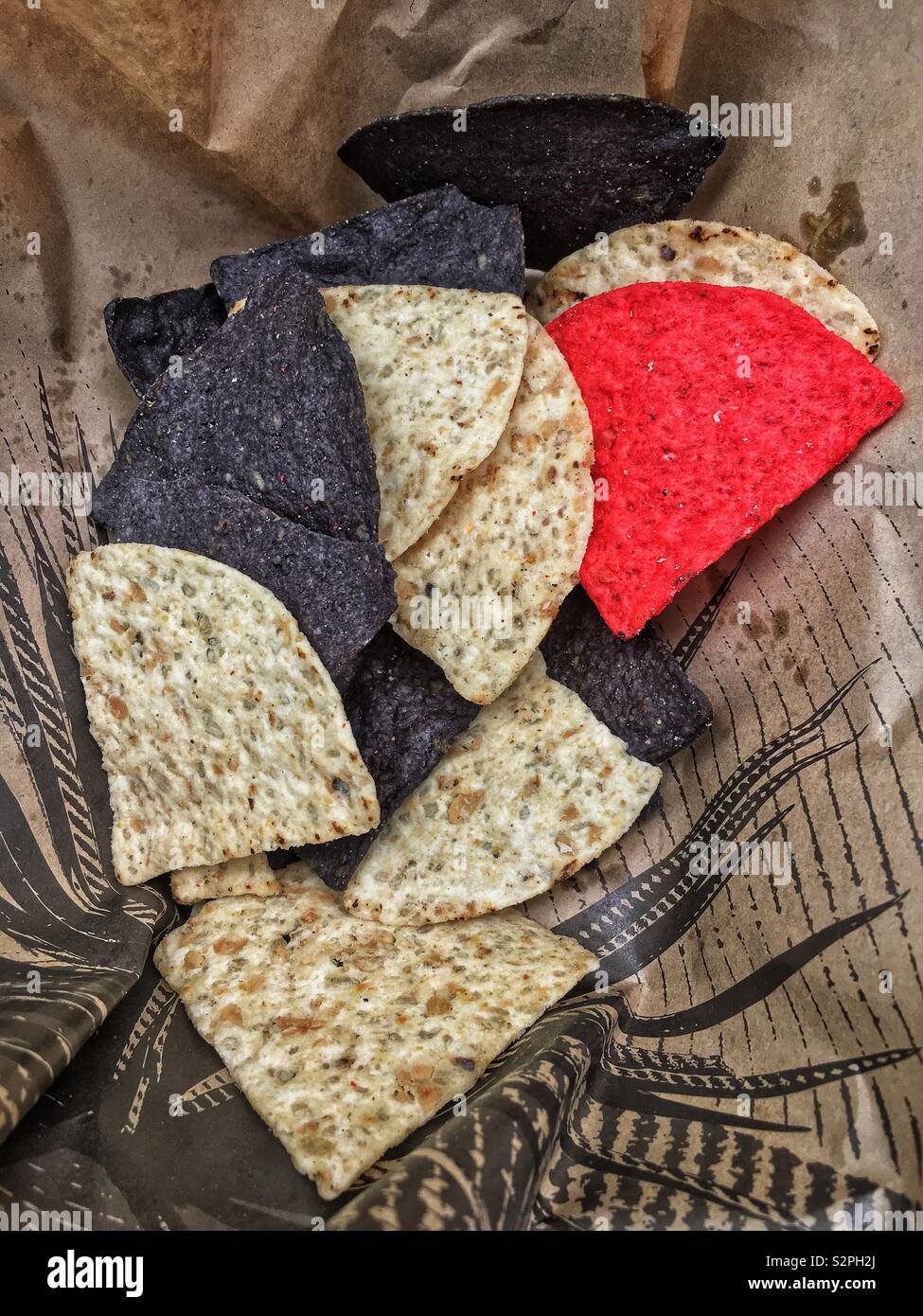 Varietà di rosso, blu e bianco corn chips imposta all'interno di una carta monouso piatto di asporto. Foto Stock