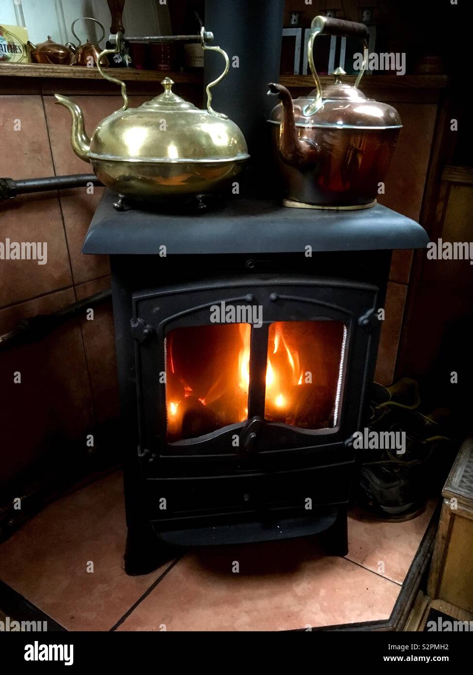 Ghisa stufa nera con un ottone e un bollitore in rame sulla parte superiore  riscaldamento dalle fiamme di un caldo il fuoco nella stufa Foto stock -  Alamy
