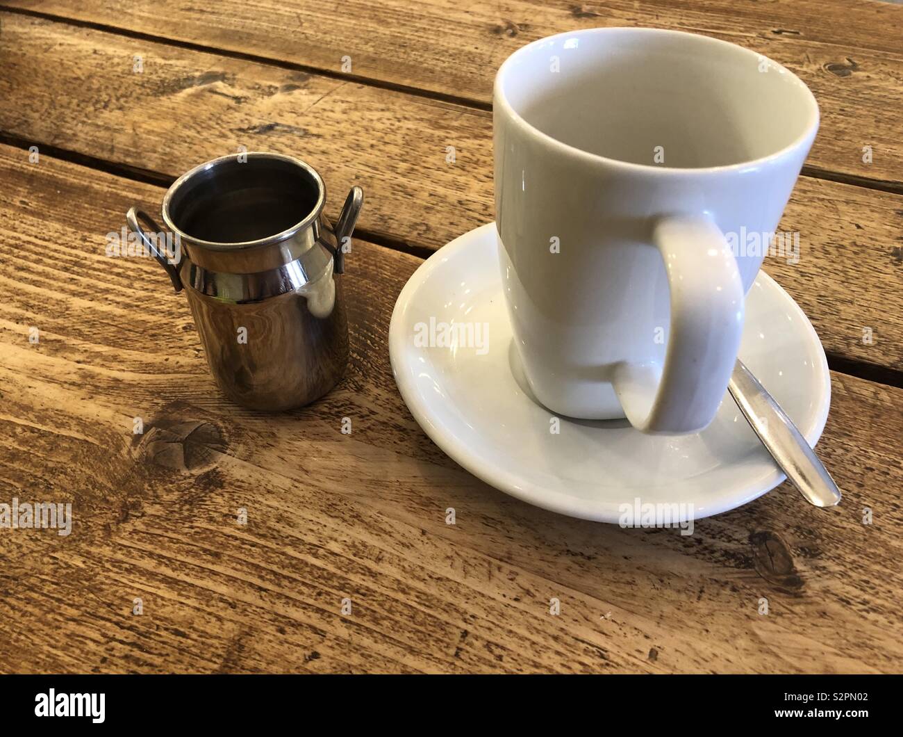 Svuotare tazza da caffè con latte churn accanto a - Immagine stock catturata con smartphone