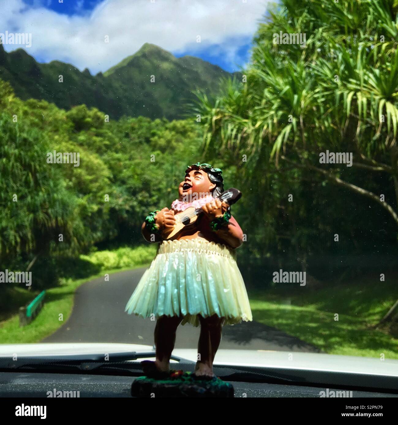 Hula bobblehead in un mantello di erba su un cruscotto di automobile giocando l'ukulele mentre si guida in Hawaii Foto Stock