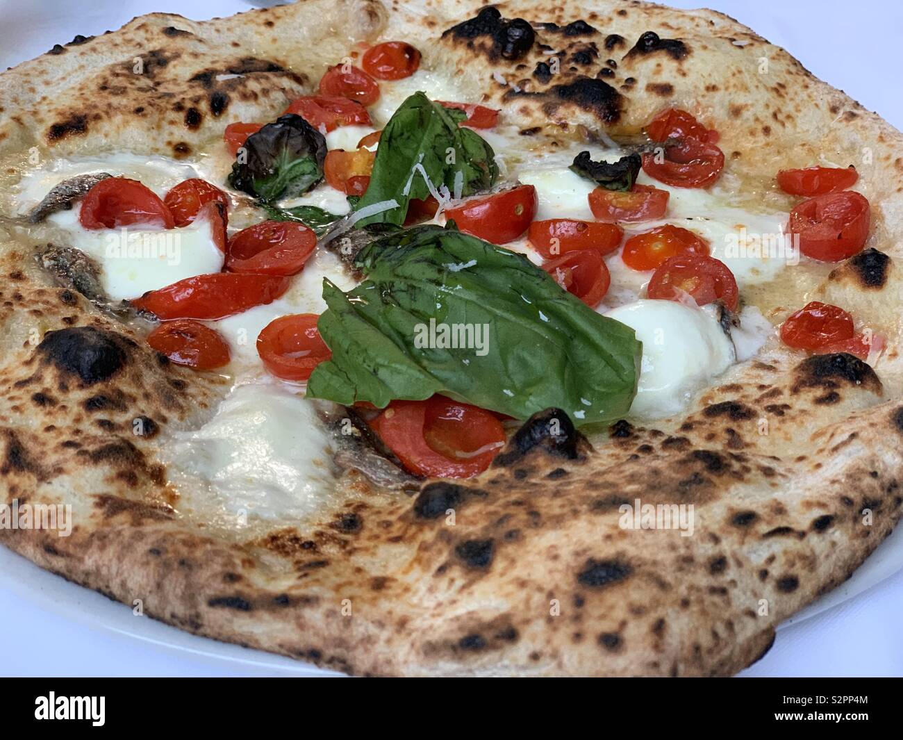 Pizza con mozzarella di bufala, pomodorini e basilico Foto Stock