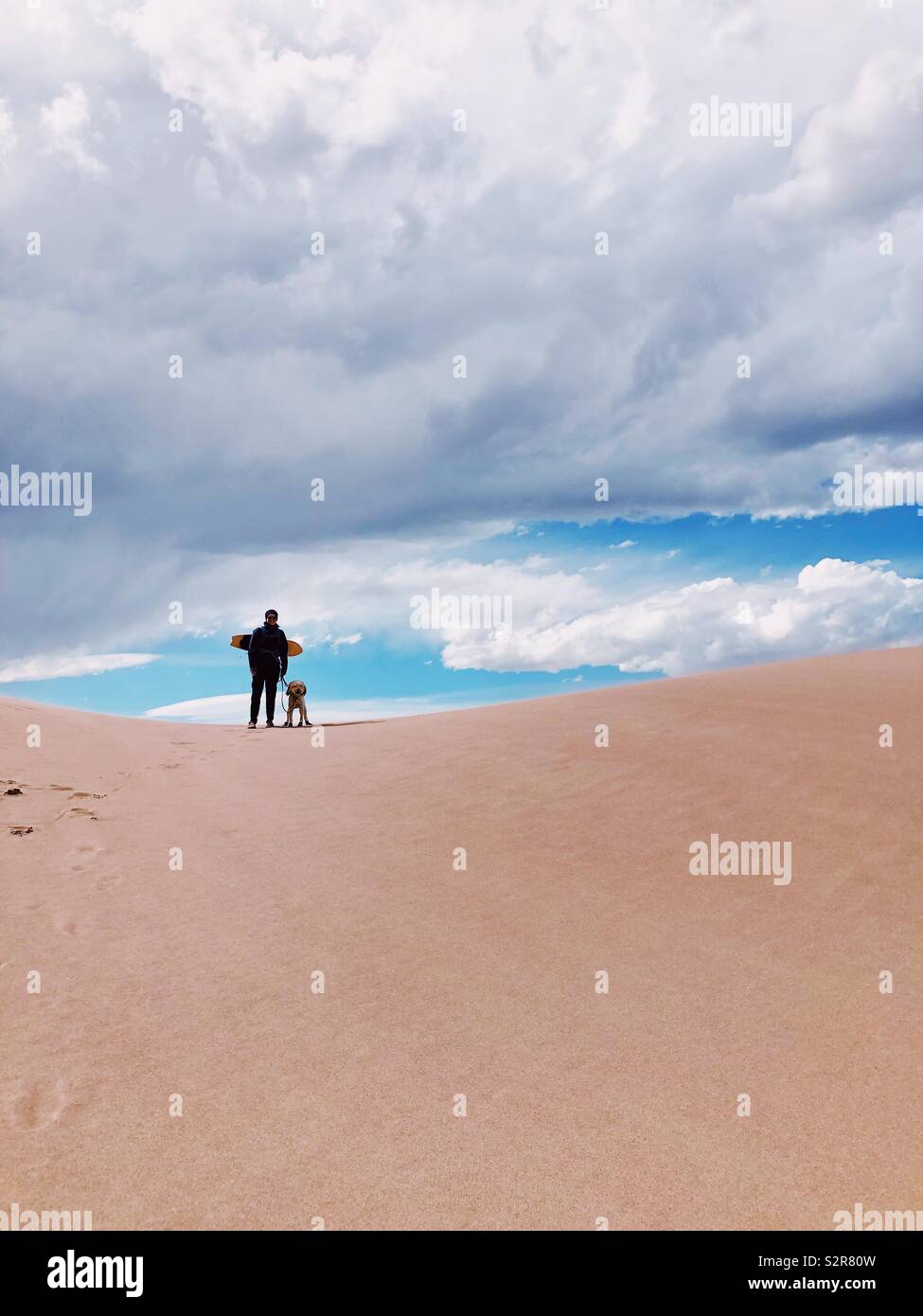 Donna e cane silhouette permanente sulla parte superiore della duna di sabbia alla grande duna di sabbia Monumento Nazionale in Colorado Foto Stock