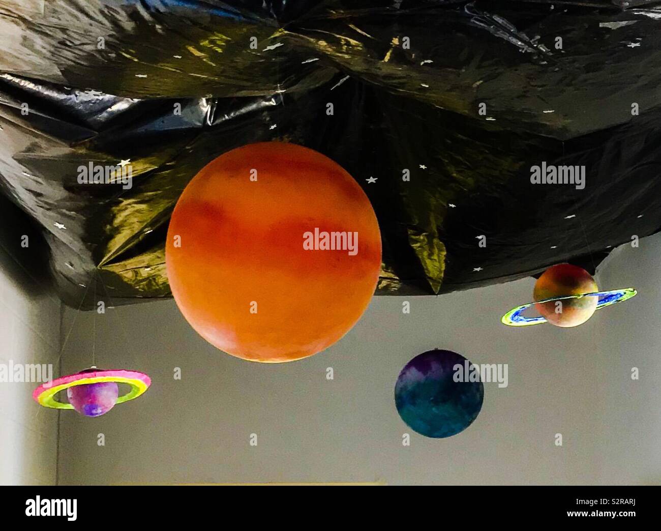 Dipinto di sfere di plastica per i pianeti e il nero teloni di plastica con bloccato sulle stelle per lo spazio esterno decorazione per la vacanza Scuola Biblica - Immagine stock catturata con smartphone