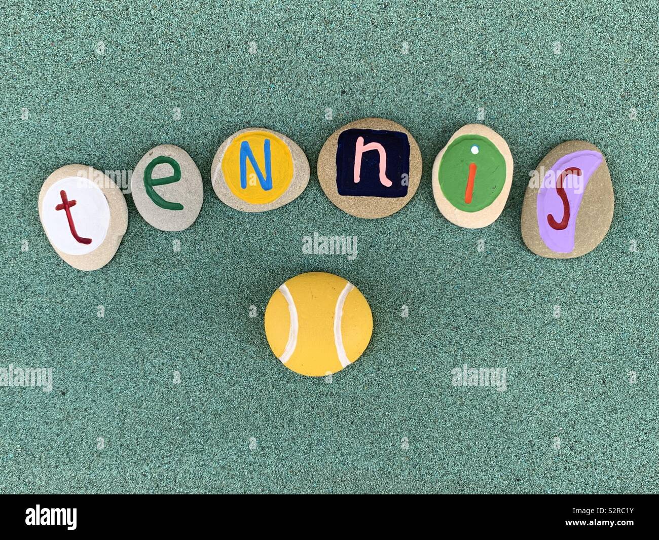 Campo da tennis testo composto con colorate e pietra intagliata lettere sulla sabbia verde Foto Stock