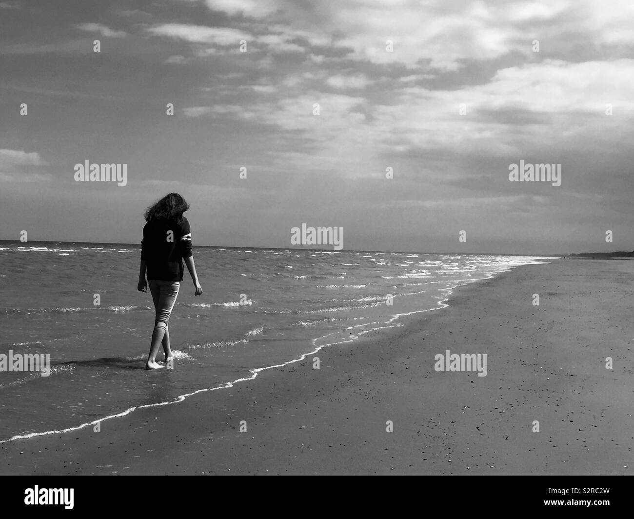 Ragazza camminare lungo la spiaggia, la passeggiata costiera, kayak in mare, lone ragazza camminare, cielo, mare, sabbia, spiaggia Foto Stock