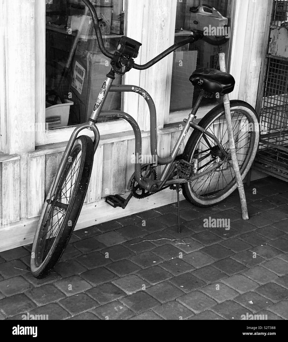 In bianco e nero di vecchi beach cruiser bicicletta parcheggiata fuori del negozio Foto Stock