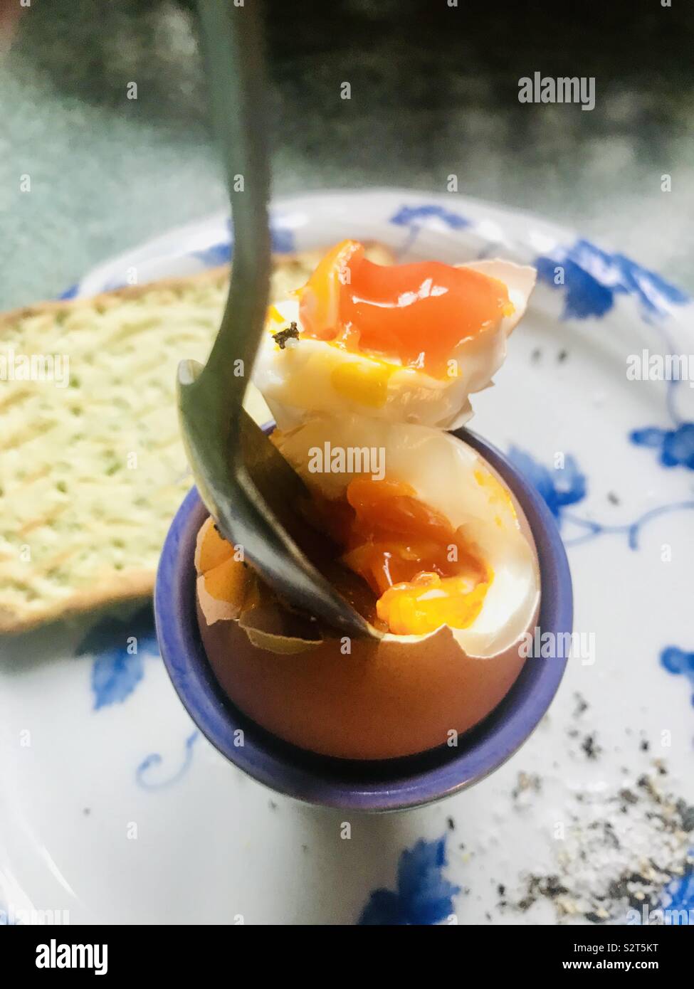 Free range Cornish uovo su blu e piastra bianca per la prima colazione con pane tostato e un cucchiaio a tuffo - Immagine stock catturata con smartphone