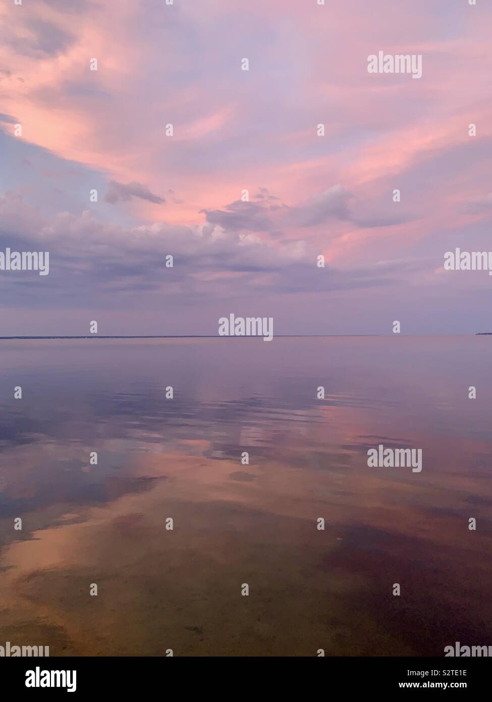 Pastello nuvole al tramonto con riflessioni sulla baia di acqua - Immagine stock catturata con smartphone