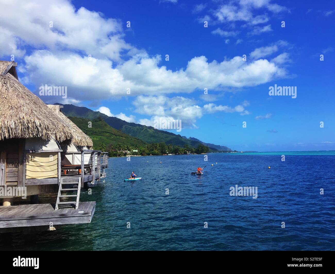 Bungalow Overwater e persone su un kayak e pagaia pensione presso un resort di Moorea, Polinesia francese. Foto Stock