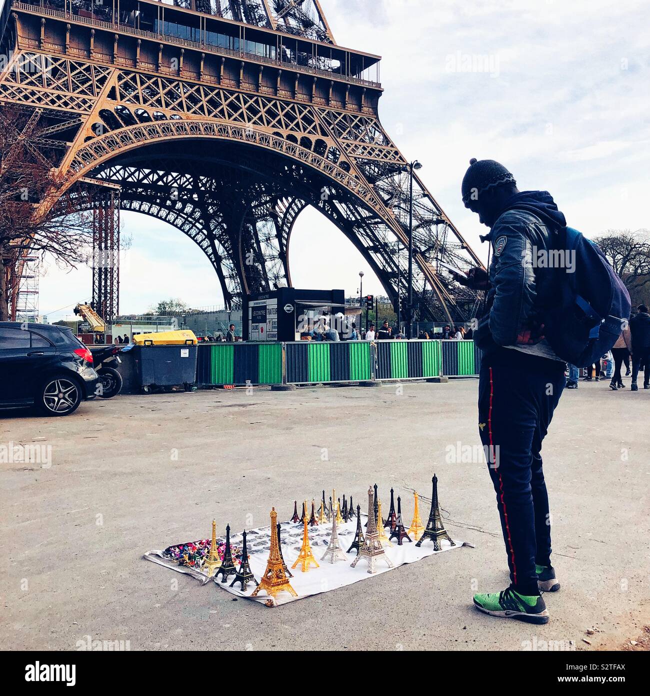Negozio di souvenir venditore controllando il suo telefono ai piedi della Torre Eiffel a Parigi - Immagine stock catturata con smartphone