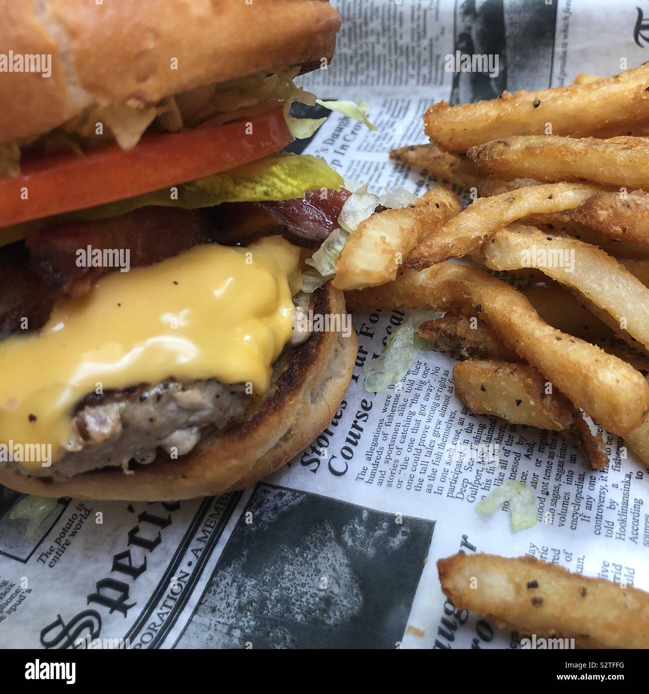 Un cheeseburger e patatine fritte su una carta da giornale Foto Stock