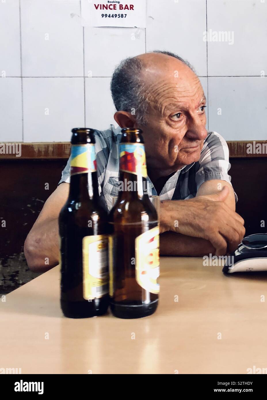 Il vecchio uomo in un bar con un paio di birre vuote Foto Stock