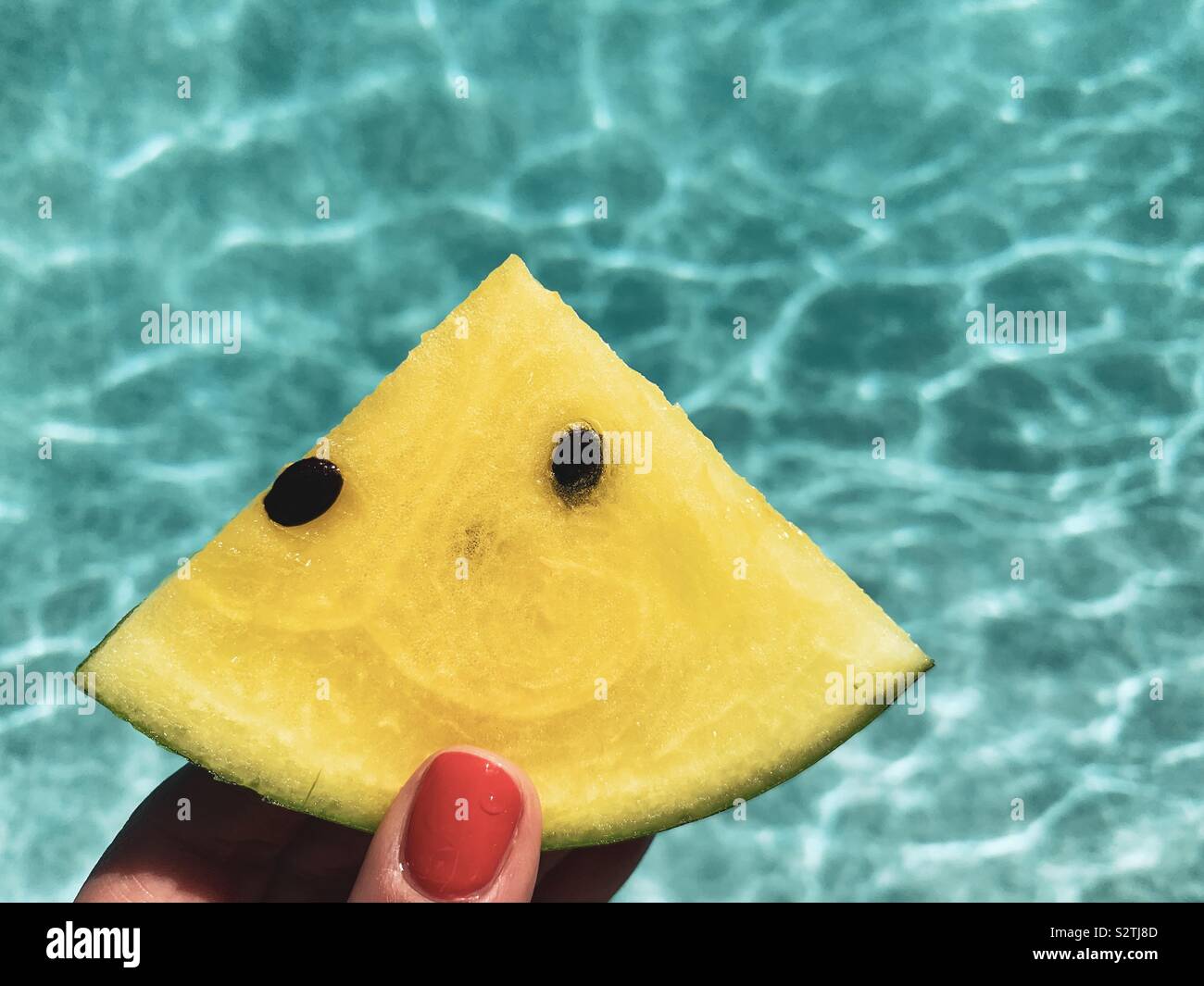In prossimità di una fetta di cocomero giallo in una donna di mano con acqua come sfondo. Foto Stock