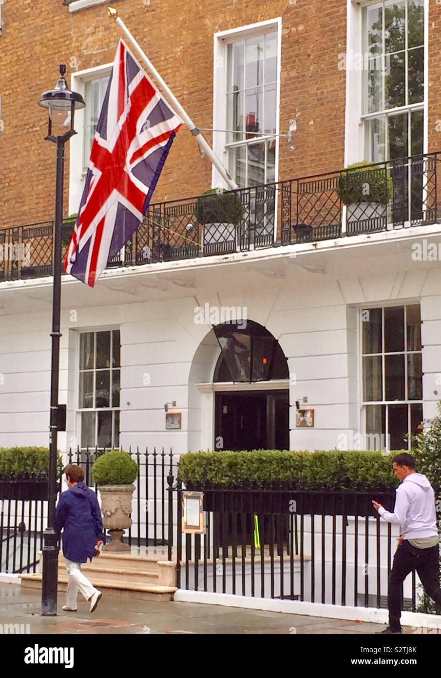 Un Union Jack vola sopra l'entrata di un hotel nel centro di Londra, Regno Unito - Immagine stock catturata con smartphone