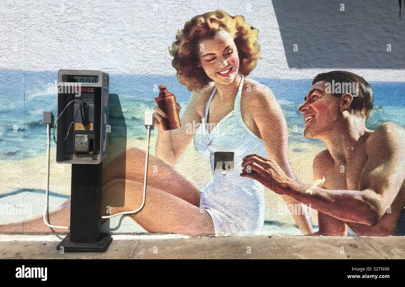 HERMOSA Beach, CA, LUG 2019: retro soft drink poster artistici, con l'uomo che assomiglia a Ronald Reagan, dipinta sulla parete con telefono a gettoni al di fuori di un negozio vicino alla spiaggia in California del Sud - Immagine stock catturata con smartphone