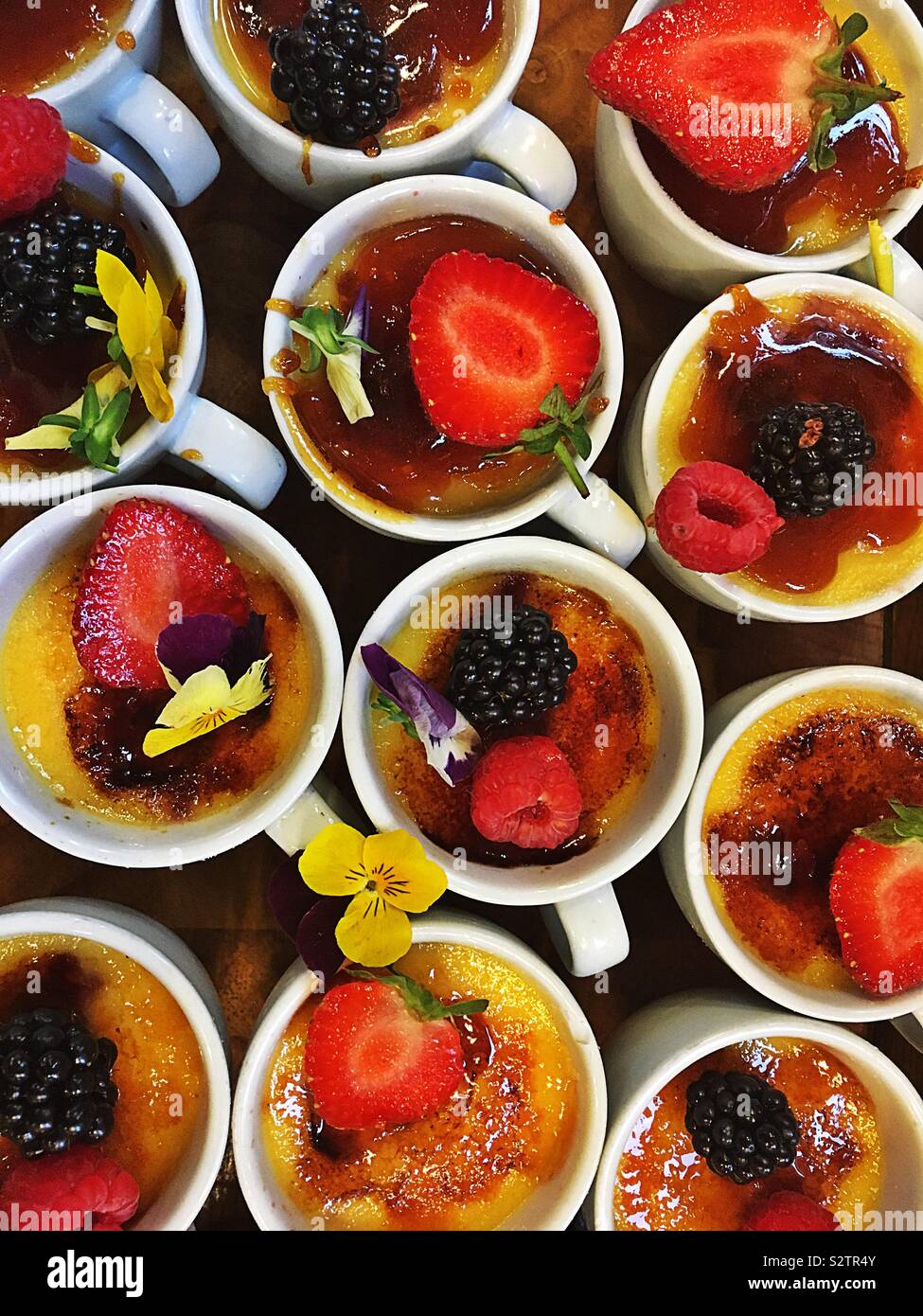 Bella estate dolci di frutta decorata con fiori e frutti. Creme brulee - Immagine stock catturata con smartphone